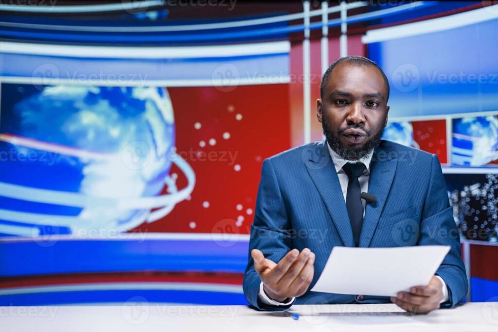 Professional news anchor dressed in formal blue suit and tie sitting at news desk, reporting on latest world news and breaking international news stories with globe graphics and digital displays visible in studio background